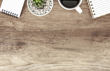 Wooden desk with a notebooks, coffee and cactus