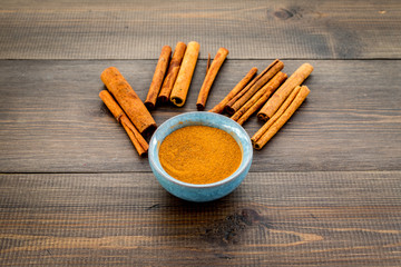 Cinnamon seasoning. Sticks and powder on dark wooden background copy space