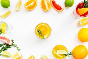 Concept of alcoholic cocktail with fruits. Glass with beverage near oranges, grapefruit, lime and rosemary on white background top view pattern