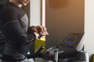 Unrecognizable man using fitness tracker in gym