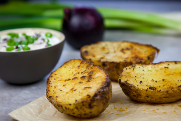 Baked jacket potatoes. Bowl with curd decorated with spring onion and red onion on the backgound