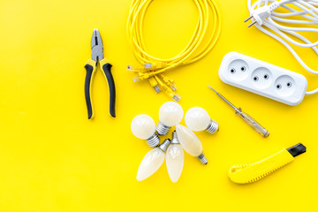 Electrical accessories at home. Bulbs, socket outlet, cabel on yellow background top view copy space