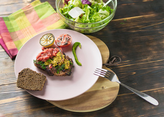 Grilled meat and salad of fresh vegetables on a plate on a wooden background.