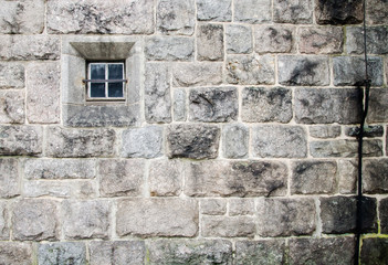 Fototapeta na wymiar old church stone wall with small window texture background