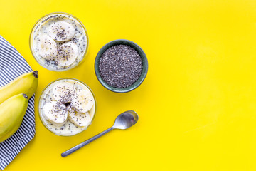 Idea for healthy breakfast. Banana pudding with chia seeds on yellow table with blue tablecloth top view copy space