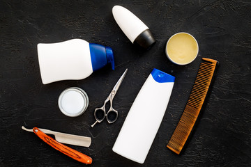 Men's set for everyday body, facial and hair care. Shampoo, gel, tools for brushing, sciccors, comb on black background top view