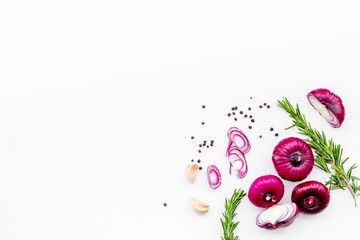 Red onion among spices rosemary, garlic, black peper on white background top view space for text