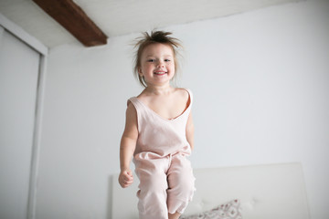 funny girl toddler lifestyle smile jumping on bed