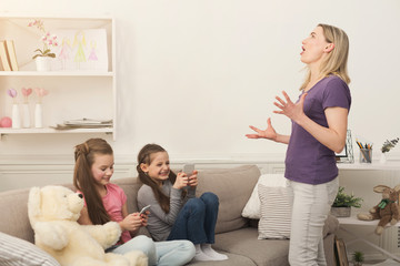 Mother feeling angry while little girls using mobile phones