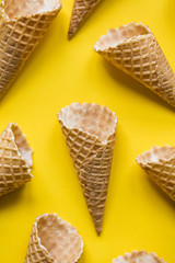Empty waffle wafer ice cream cone on a bright yellow background