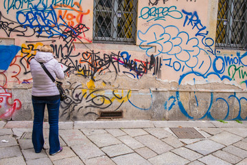 Persona che guarda un muro esterno di un’abitazione imbrattato da scritte