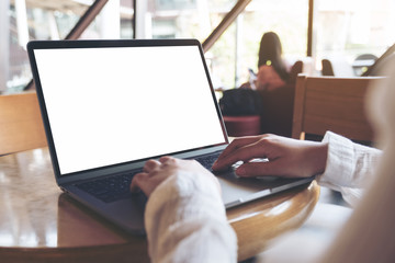 Mockup image of business woman using and typing on laptop with blank white desktop screen in cafe