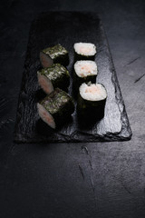 sushi rolls with salmon covered in nori on dark background. Asian cuisine and Japanese food concept