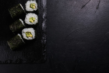 sushi rolls with salmon covered in nori on dark background. Japanese traditional food preparing craft. Copy space concept