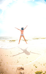 Fototapeta na wymiar A girl is jumping on the beach.