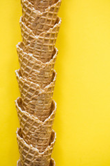 Empty waffle wafer ice cream cone on a bright yellow background