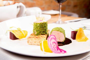 Roast pork tenderloin with crispy potato bread, marinated beetroots and green pepper sauce served in a restaurant