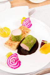 Roast pork tenderloin with crispy potato bread, marinated beetroots and green pepper sauce served in a restaurant