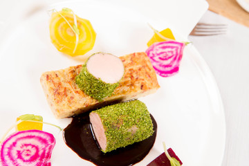 Roast pork tenderloin with crispy potato bread, marinated beetroots and green pepper sauce served in a restaurant
