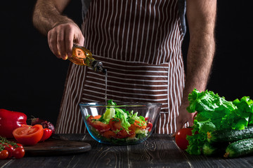 Cooking and home concept - close up of male hands flavouring salad in a bowl with olive oil