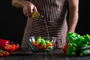Cooking and home concept - close up of male hands flavouring salad in a bowl with olive oil