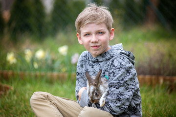 Preschool child, cute boy, playing with little rabbit outdoors