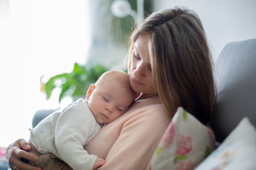 Young mother, holding tenderly her newborn baby boy