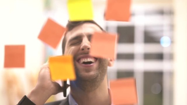 Business man making a mobile meeting with sticky note schedule on window