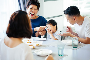 Happy Asian extended family having dinner at home full of laughter and happiness