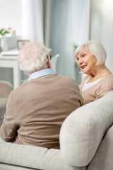 Pleasant talk. Positive senior couple looking at each other while having a pleasant conversation