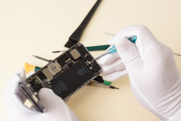 Hands of the master in white gloves dismantled screwdriver smartphone for repair
