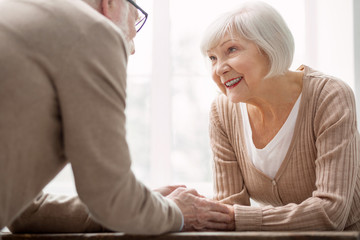 Obraz premium Always together. Cheerful nice aged woman holding her husbands hands while being together with him