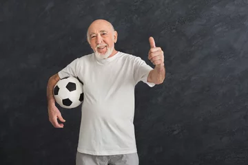 Foto op Canvas Senior man with soccer ball showing thumb up © Prostock-studio