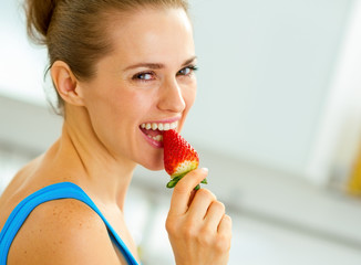 happy young woman eating strawberry