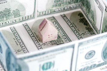 The concept of a toy house on the background of dollar bills