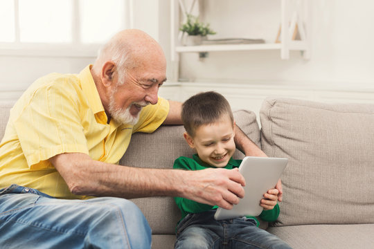 Senior man watching videos on tablet with grandson