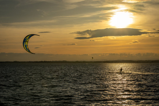 Un kitesurfer sous un coucher de soleil orange