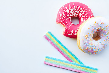 Bitten pink donut and jelly candies on the white background isolated. Copy space.