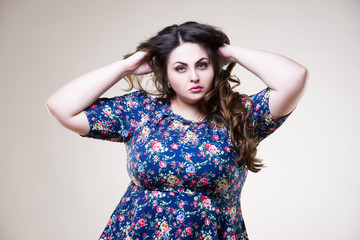 Plus size fashion model in casual clothes, fat woman on beige background, overweight female body