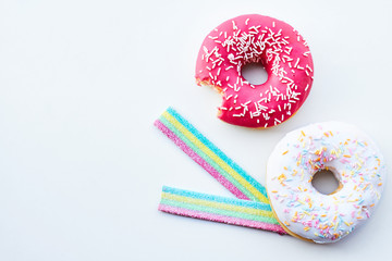 Bitten pink donut and jelly candies on the white background isolated. Copy space.