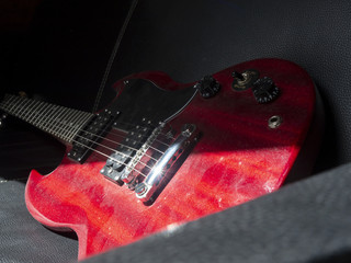 Dusty red guitar on couch - obrazy, fototapety, plakaty