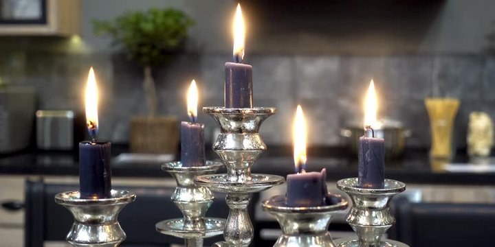4K view of burning candles in a silver candelabra against a background of a home interior.