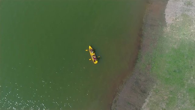 Aerial birds eye view of family riding a cayak together, rowing and crossing the green water