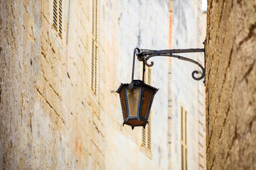 Malta, Mdina. Old lantern lamp in the medieval city with the narrow streets and houses limestone facades