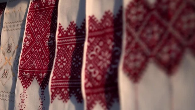 National Ukrainian rushnyk in warm sunlight. A symbol of Ukraine, traditional ethnic towel with hand embroidered ornament pattern. White cloth with multicolor needlework texture, close-up. 