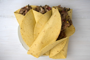 Fajitas consisting of chicken stew with red and green pepper, with red onion, pickled cucumber and spices wrapped in a corn cake.