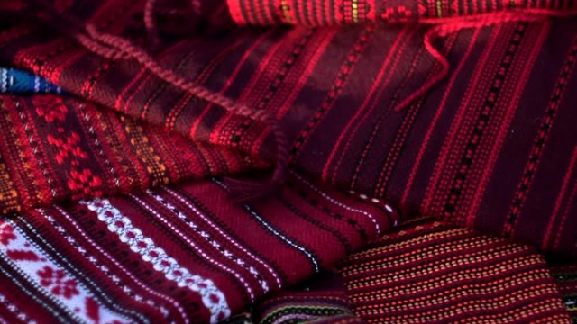 A symbol of Ukraine, national Ukrainian krayka in warm sunlight. A traditional ethnic woven belt with hand embroidered ornament pattern. A thick cloth with multicolor needlework texture, close-up. 