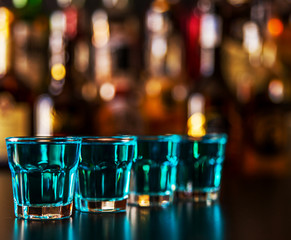 Popular blue drink shot kamikaze on the background of the bar with bottles, a refreshing drink