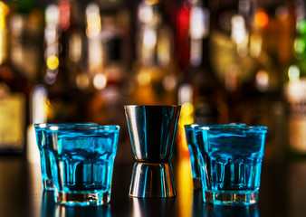 Popular blue drink shot kamikaze on the background of the bar with bottles, a refreshing drink
