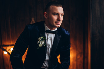 Fototapeta premium Portrait of young groom with wooden background